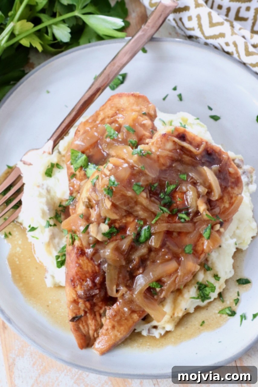 Rich Slow Cooker French Onion Chicken 10 Cooked French Onion Chicken breast on a plate with mashed potatoes.