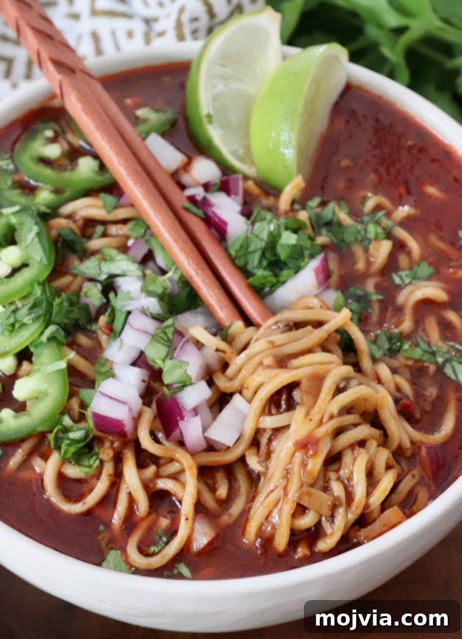 cooked ramen noodles in beef broth in bowl topped with diced onions and sliced jalapenos