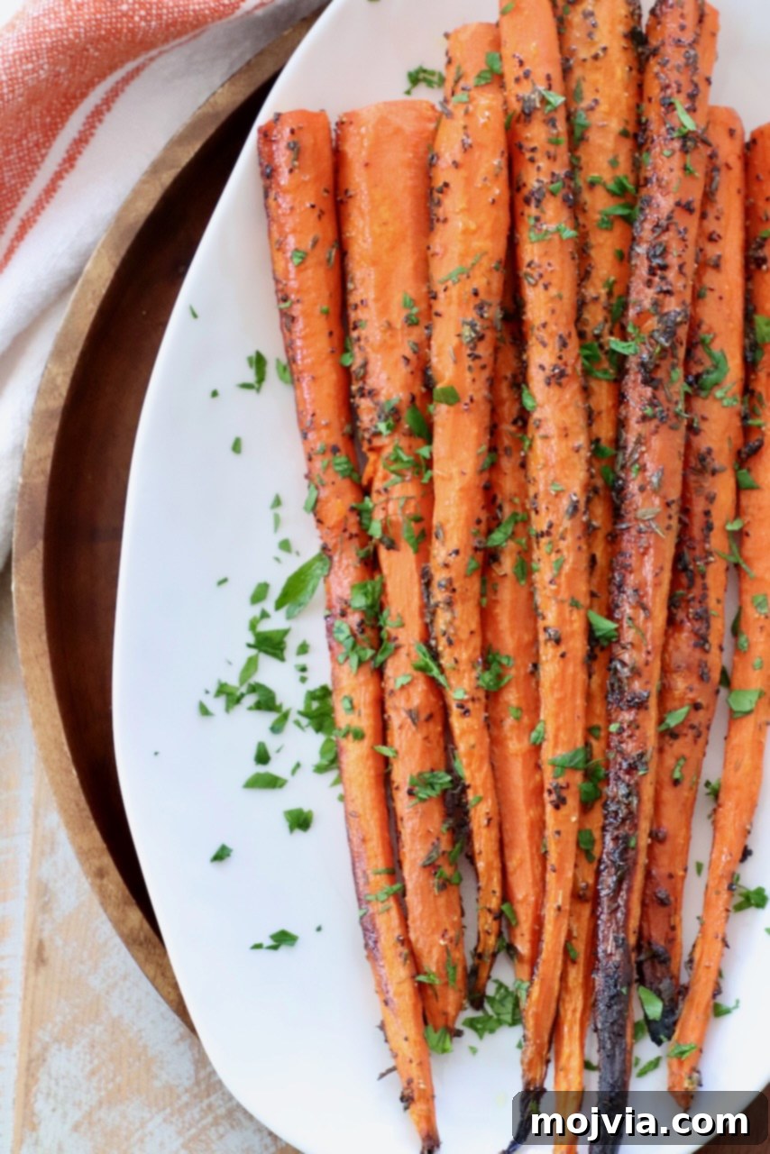 whole roasted carrots on a white plate with fresh herbs as garnish