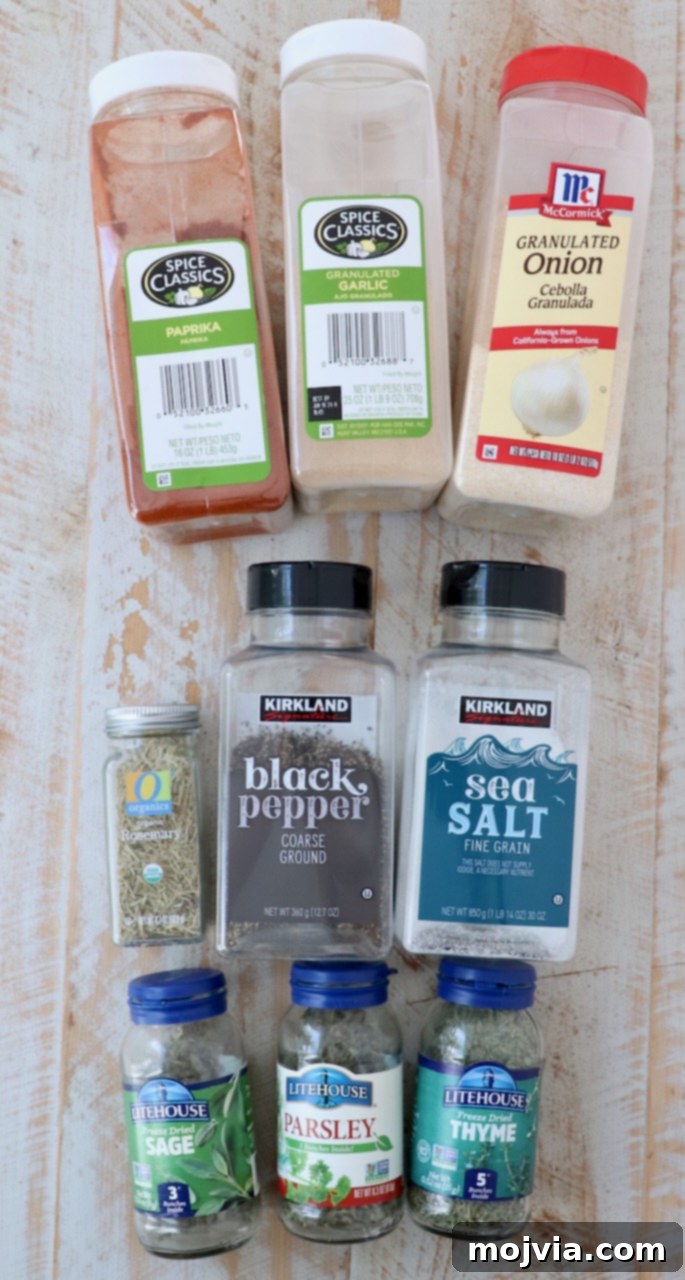 A collection of fresh ingredients for homemade turkey seasoning arranged on a rustic white wooden board.