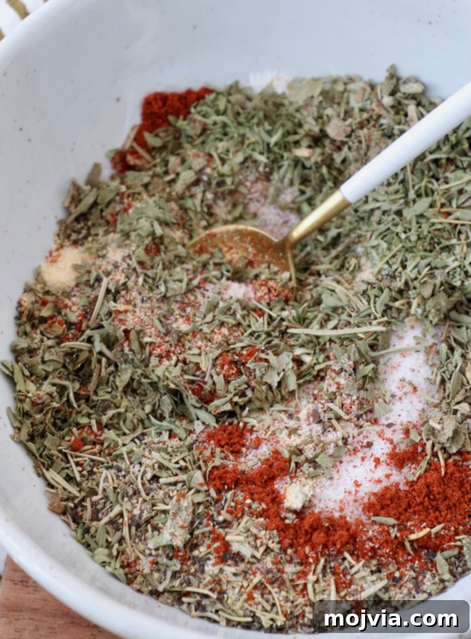 Freshly mixed herbs and spices for turkey seasoning in a bowl with a spoon, showcasing its perfect blend.