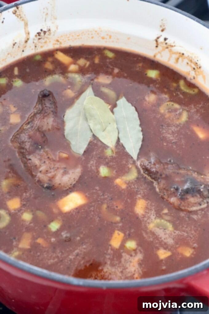 Melt-Off-The-Bone Guinness Short Ribs 9 short ribs in liquid in dutch oven with bay leaves on top
