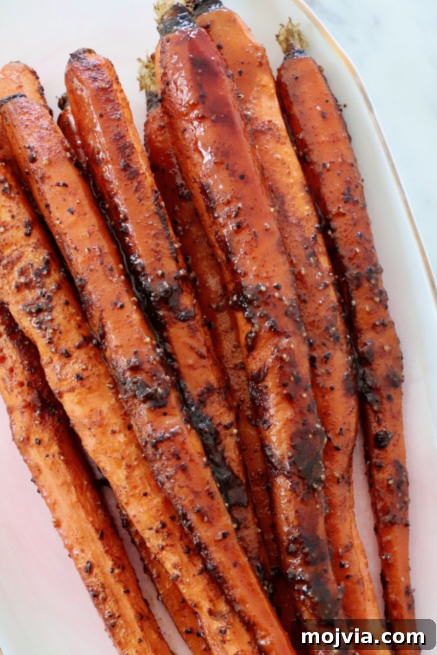 Roasted, seasoned carrots on a plate, glistening with honey glaze.