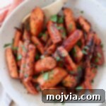 Roasted honey glazed carrots in a bowl with a serving spoon