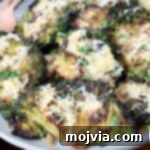 Smashed broccoli topped with Parmesan cheese on a plate, ready to be served