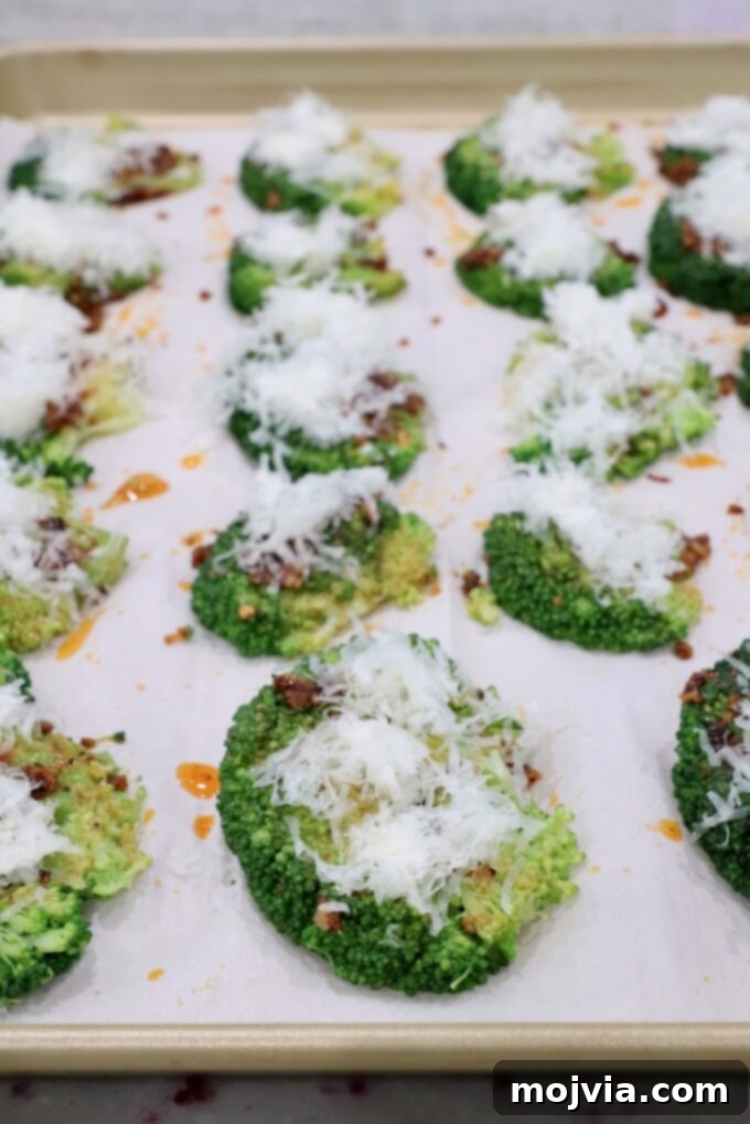 Crispy Smashed Broccoli 9 Smashed broccoli florets on a baking sheet, generously topped with grated Parmesan cheese