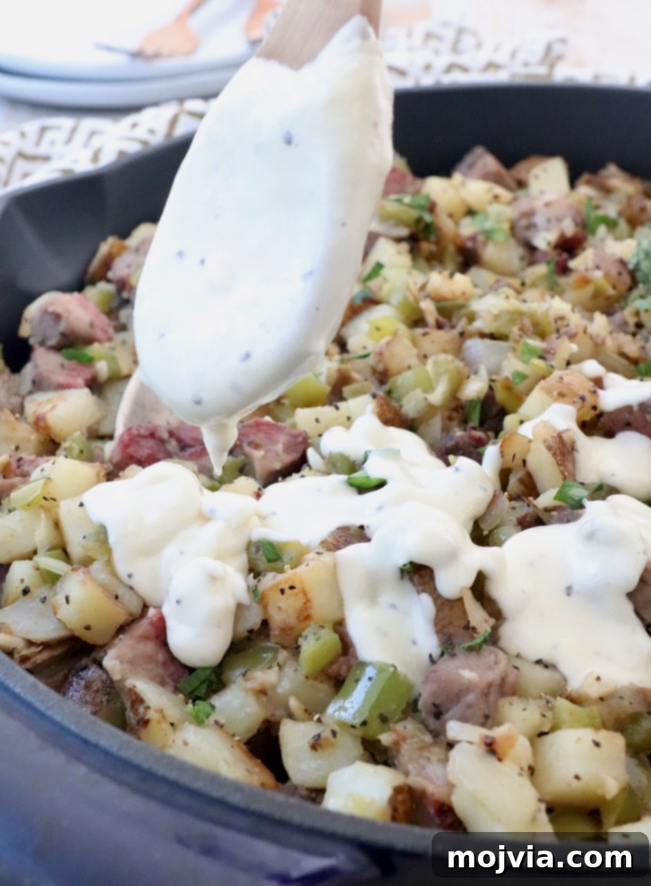 Philly Cheesesteak Skillet 9 cheese sauce in spoon drizzled over potato hash in skillet
