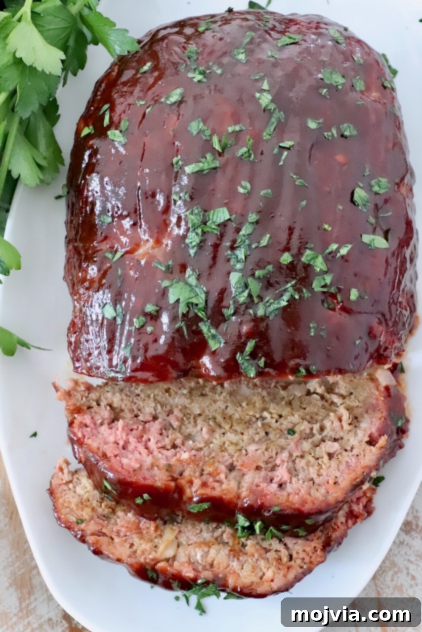 Pitmaster's Smoked Meatloaf 2 glazed smoked meatloaf sliced on plate, showcasing its juicy interior and perfect smoke ring