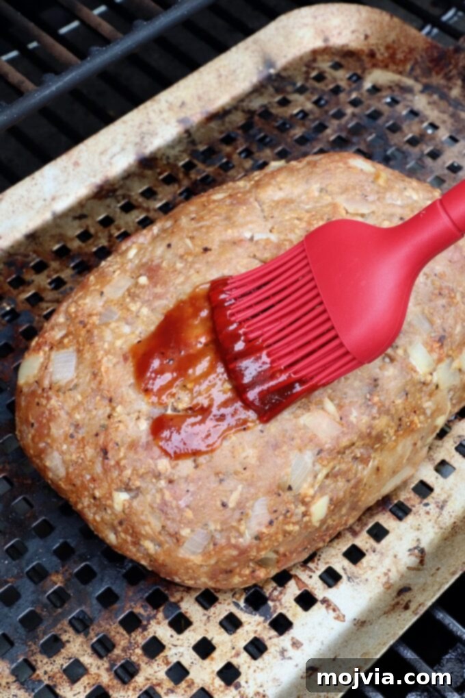 Pitmaster's Smoked Meatloaf 8 meatloaf in smoker, being brushed with BBQ sauce