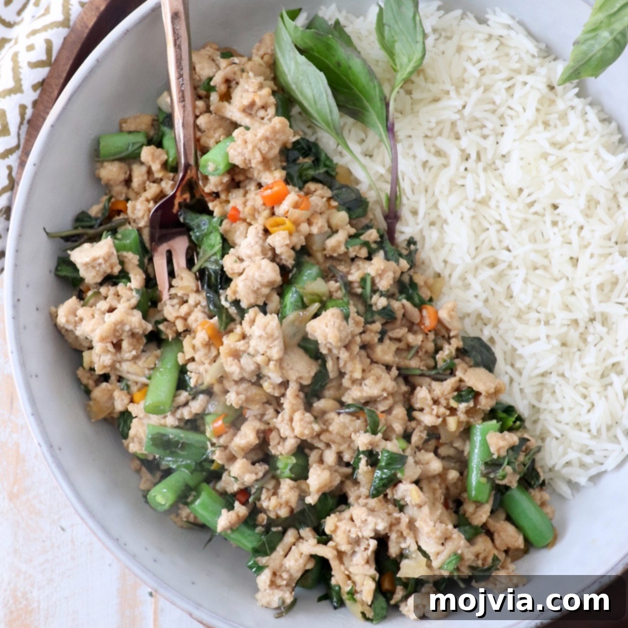 cooked ground chicken with thai basil and green beans in bowl with cooked white rice