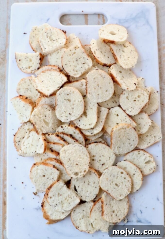Toasted Bagel Crisps 4 Thinly sliced bagel rounds on a cutting board, neatly arranged and ready for seasoning.