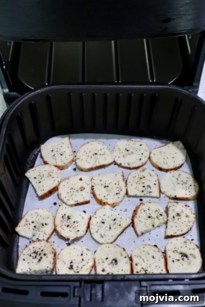 Toasted Bagel Crisps 6 Perfectly seasoned bagel slices carefully placed in an air fryer basket, ready for quick cooking.