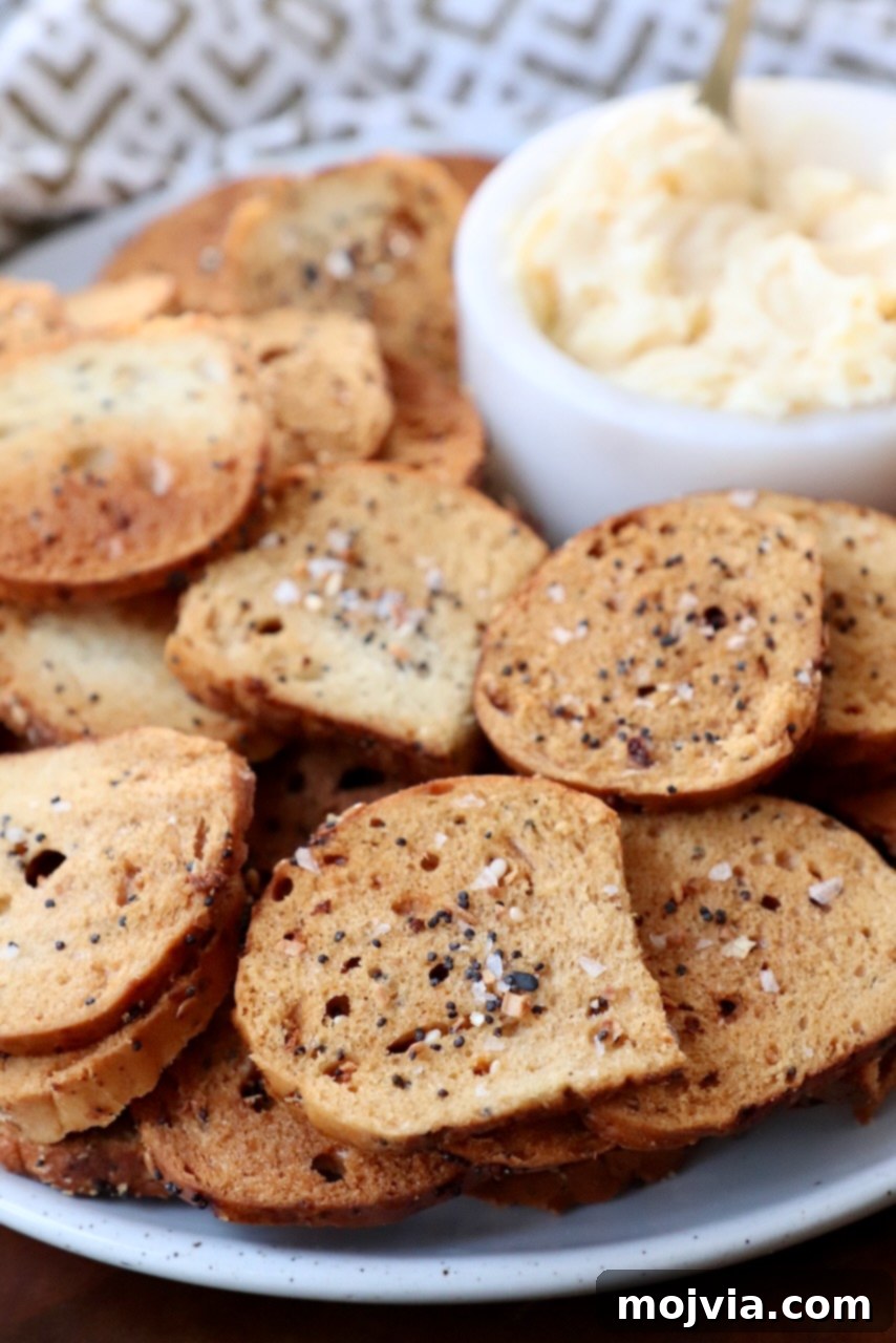 Toasted Bagel Crisps 7 A plate of homemade bagel chips artfully arranged with a small bowl of creamy cheese spread, ready to be enjoyed.