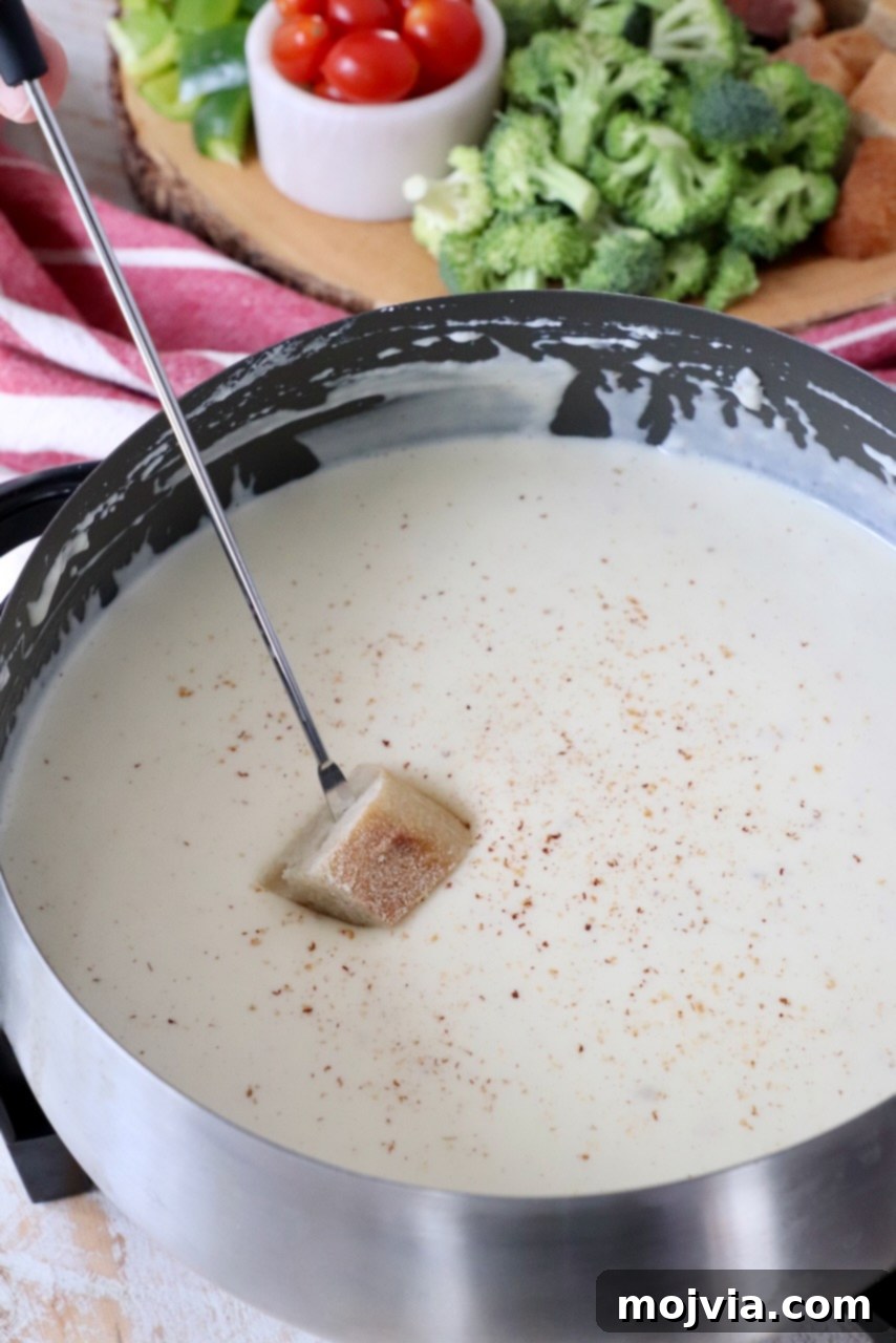 piece of bread dipped into cheese fondue in fondue pot