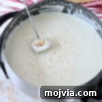 piece of bread dipped into cheese fondue in pot