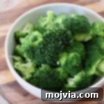 Flawless Steamed Broccoli in Minutes 10 Freshly steamed broccoli florets in a bowl, showcasing vibrant green color.