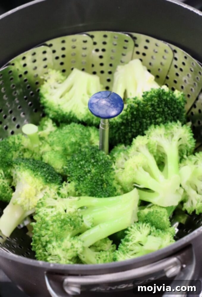 Flawless Steamed Broccoli in Minutes 6 Close-up of vibrant green, freshly steamed broccoli in a steamer basket, highlighting its tender appearance.