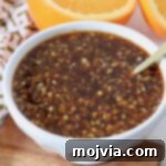 Homemade Chinese orange sauce in a small bowl with a spoon, showing its vibrant color and glossy texture.