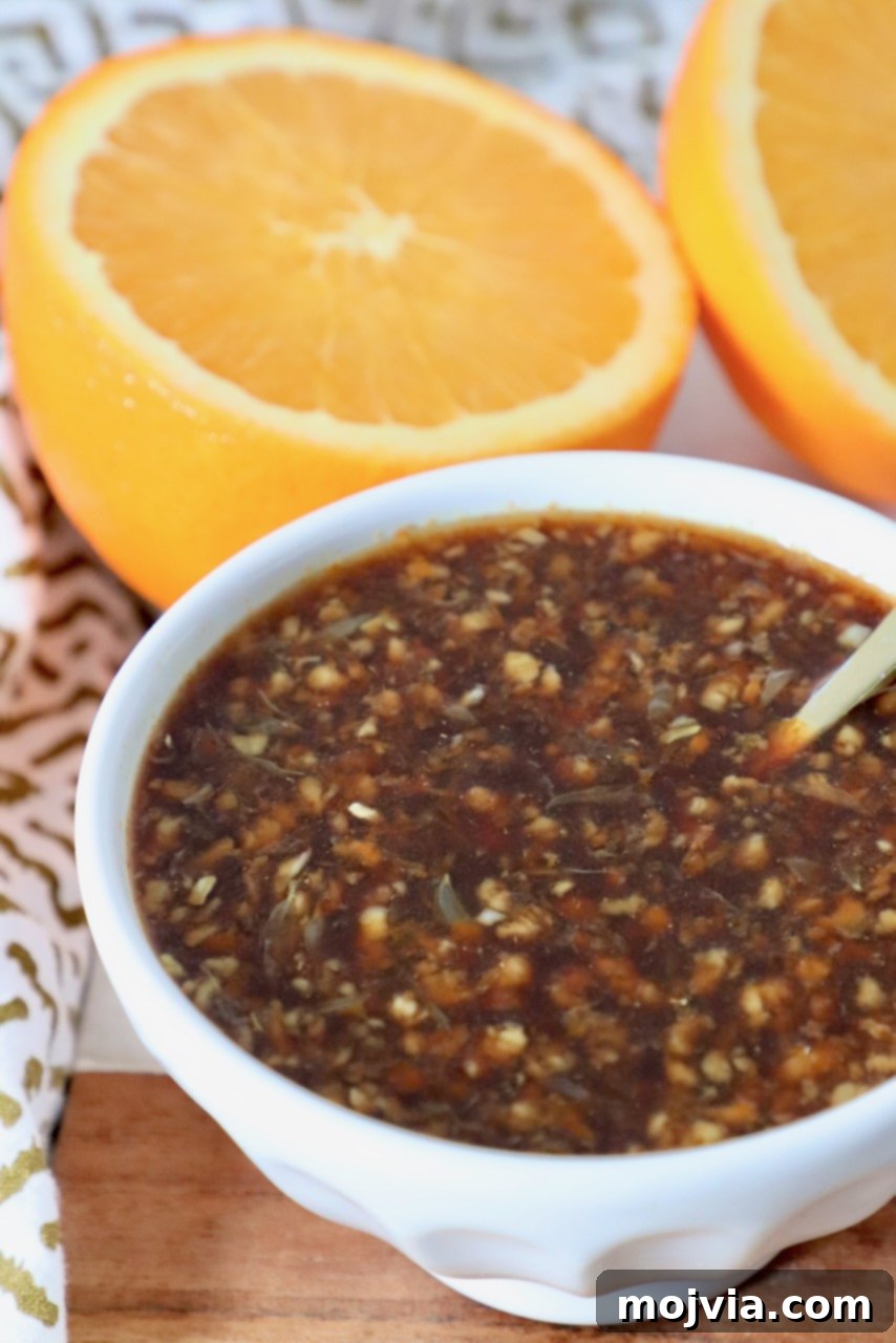 Zesty Orange Glaze 5 A small bowl of sticky, sweet, and tangy homemade Chinese orange sauce with a spoon, ready for use.
