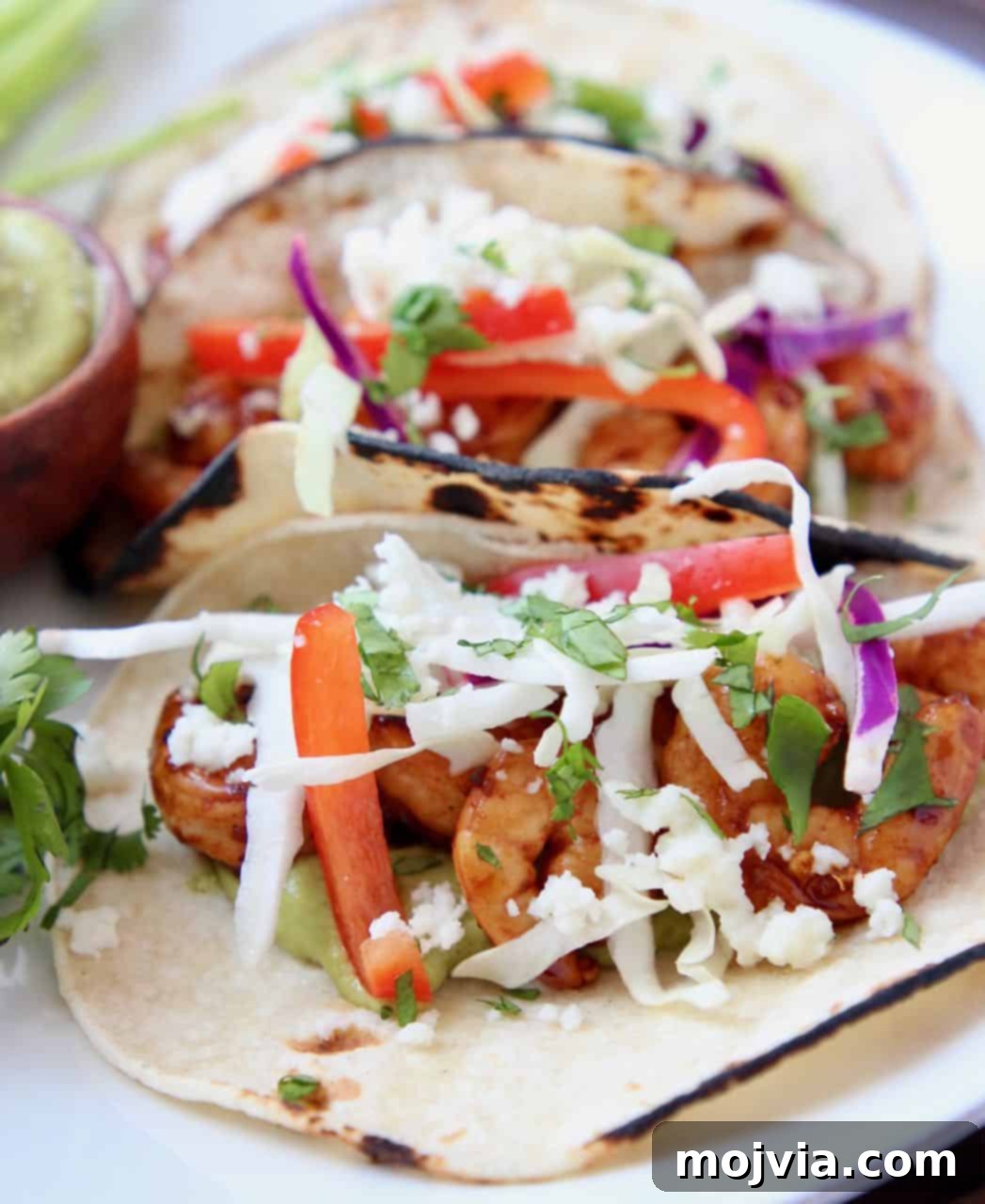 Zesty Grilled Shrimp Tacos with Creamy Avocado Salsa 2 Grilled shrimp tacos, topped with slaw on white plate