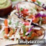 Grilled shrimp tacos in corn tortillas topped with slaw and cotija cheese