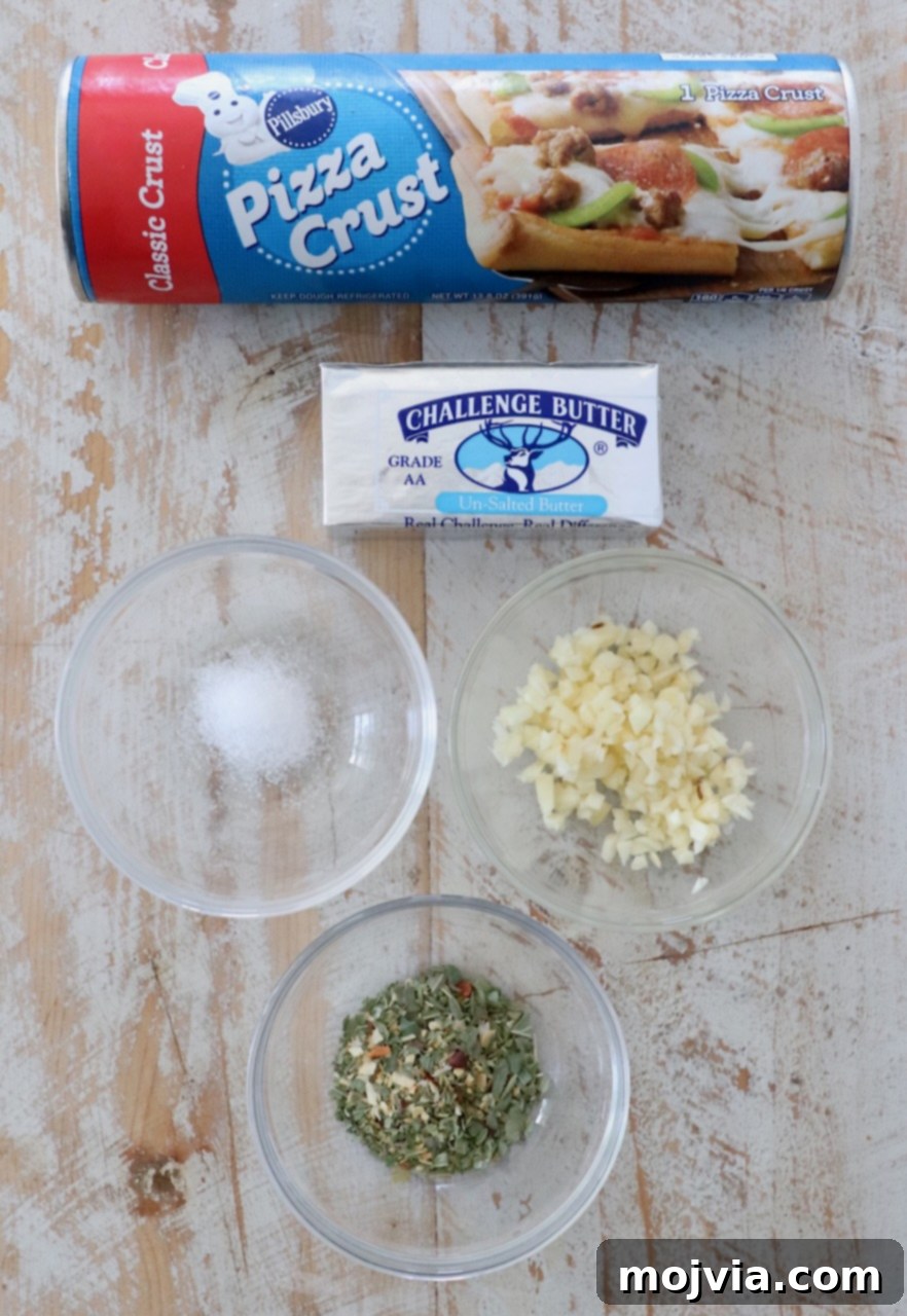 Ingredients for homemade garlic knots laid out on a white wooden board, including a can of pizza dough, butter, fresh garlic cloves, and Italian seasoning.