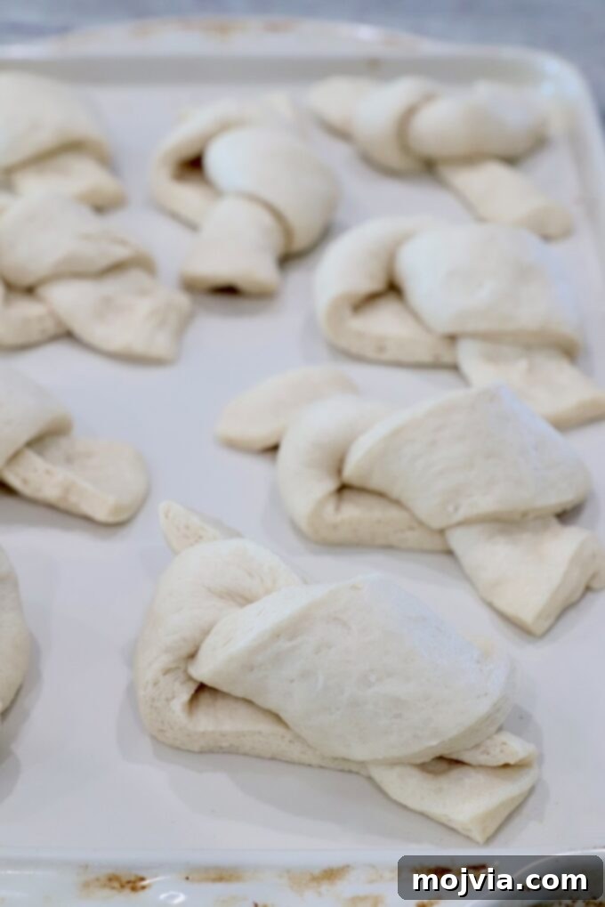 Uncooked garlic knots, neatly tied, arranged on a baking sheet lined with parchment paper.