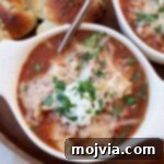 Hearty Lasagna Soup 12 lasagna soup, topped with cheese, in bowl with spoon