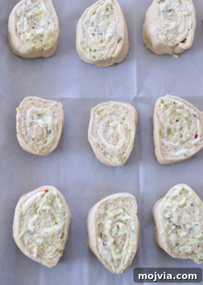 uncooked creamy pickle rolls on parchment-lined baking sheet