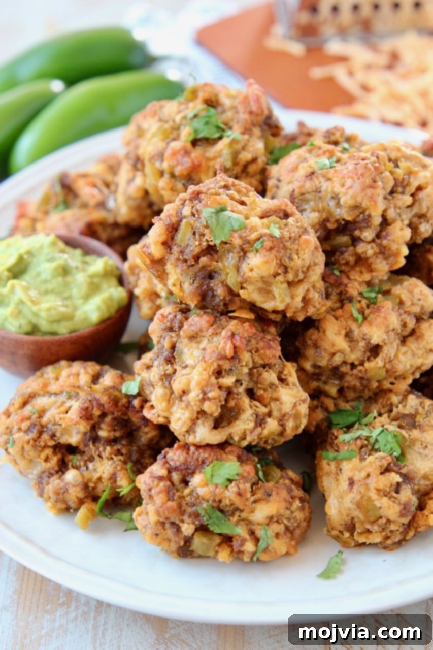 Crispy Mexican Chorizo Sausage Balls piled high on a plate, with a small bowl of creamy avocado dipping sauce