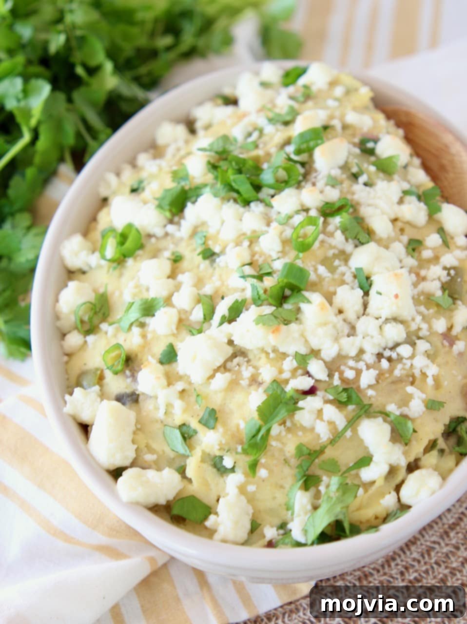 Mexican potatoes mashed in a bowl with queso fresco, diced green onions and fresh cilantro