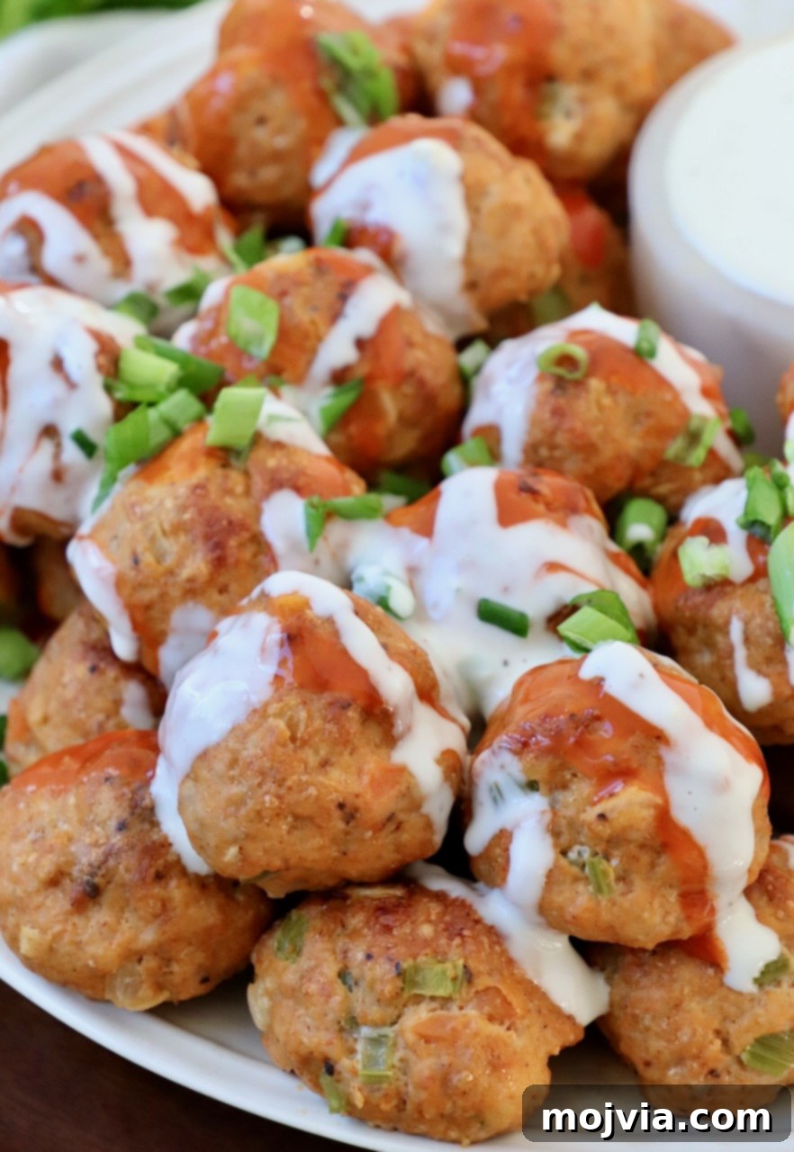 Zesty Buffalo Chicken Poppers 2 Stacked buffalo chicken meatballs drizzled with blue cheese dressing and buffalo sauce, ready to serve