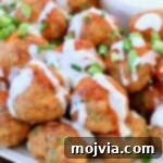 Buffalo chicken meatballs on plate, topped with a drizzle of buffalo sauce and blue cheese dressing