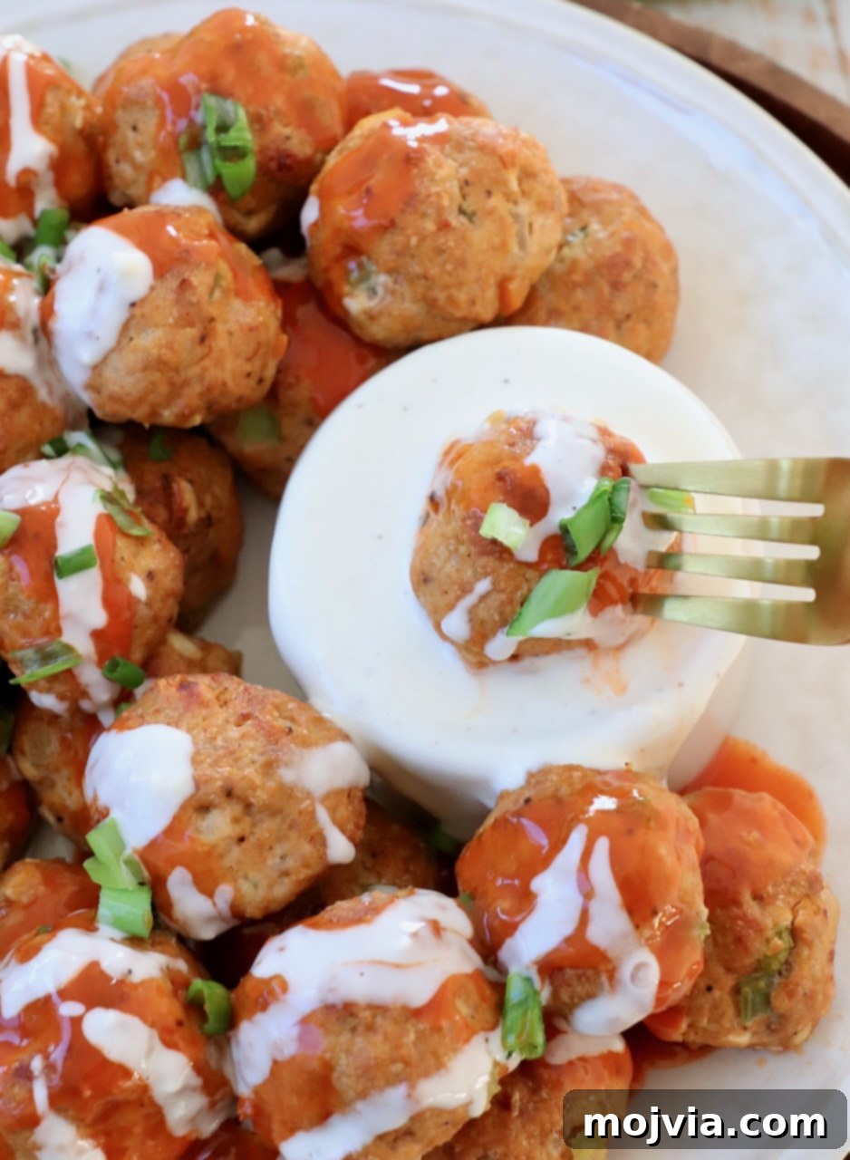 Zesty Buffalo Chicken Poppers 9 Buffalo chicken meatball on a fork, dipped into a bowl of creamy blue cheese dressing