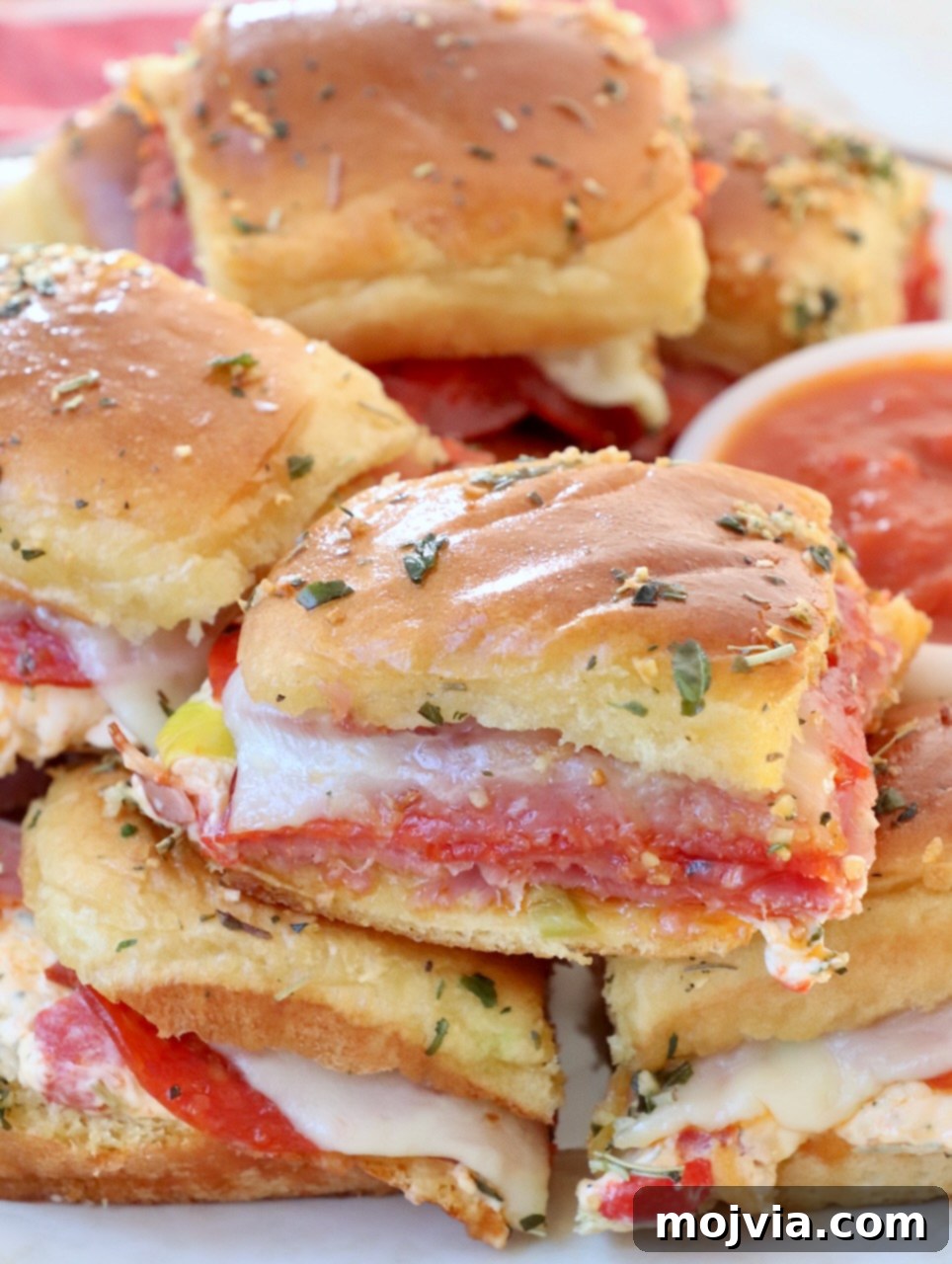 Stacked Hot Italian Sliders on a plate, showcasing their inviting layers of meat, cheese, and golden-brown buns.