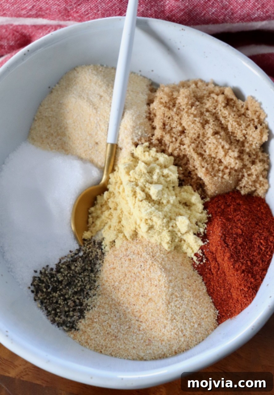 Spices and brown sugar carefully separated in a bowl with a spoon, highlighting the ingredients for a dry rub.