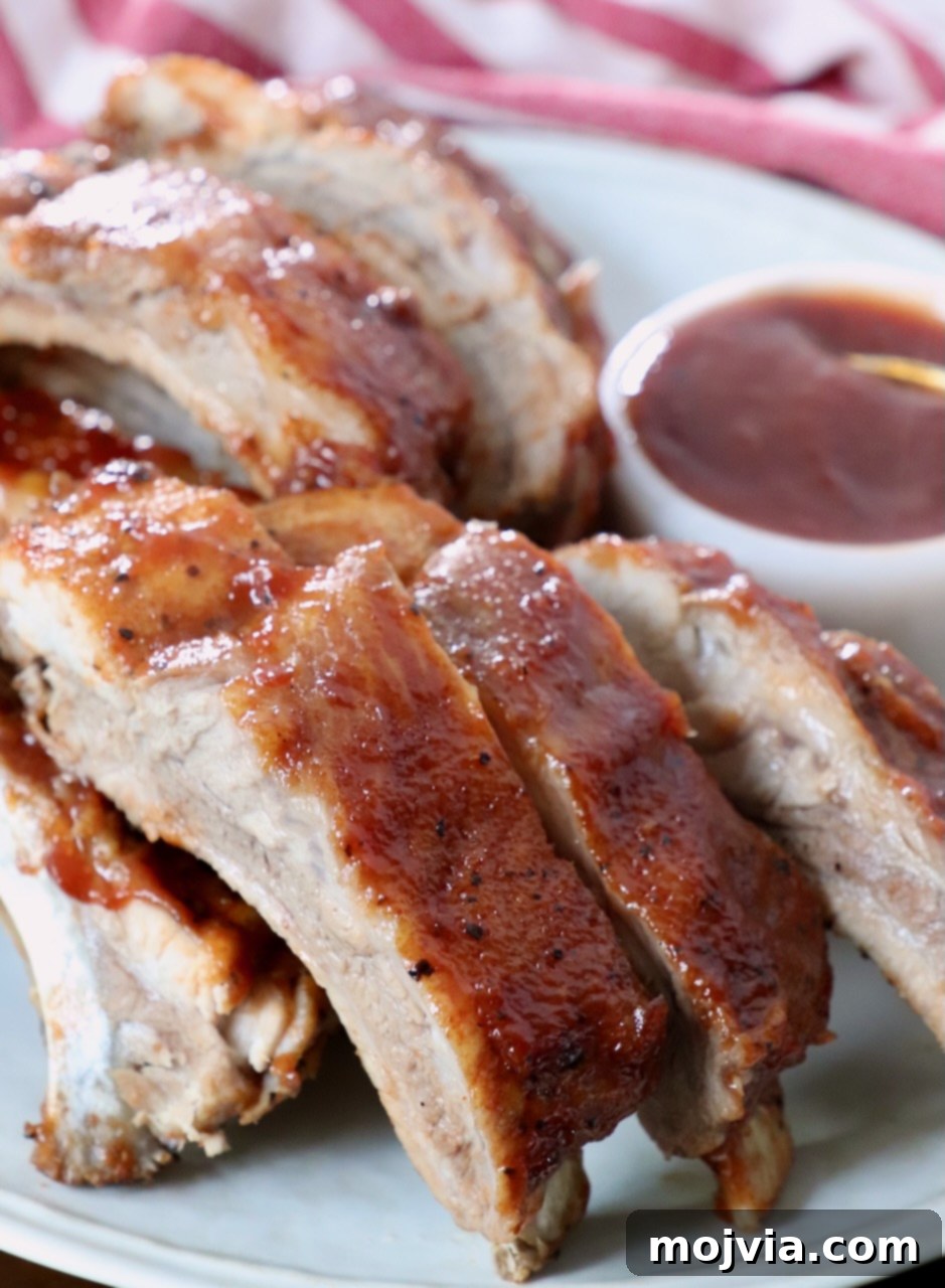 Fall Off The Bone Instant Pot Ribs 9 cooked baby back ribs brushed with bbq sauce on plate
