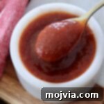 Jack Daniel's: The Taste of Tennessee BBQ 8 A small bowl of glistening Jack Daniel's BBQ sauce with a small spoon, showcasing its rich texture.