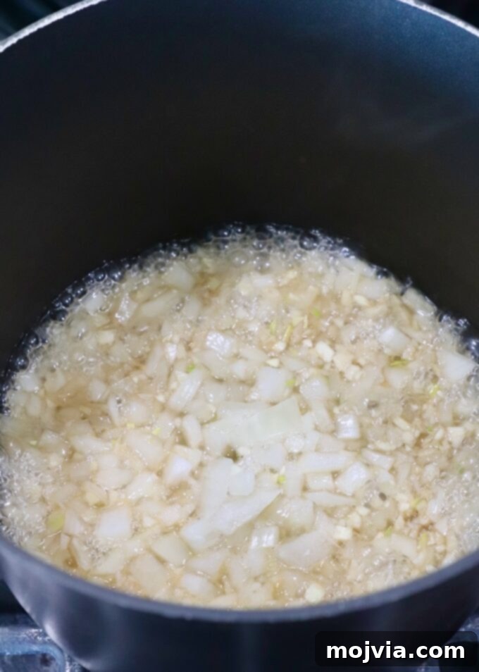 Jack Daniel's: The Taste of Tennessee BBQ 4 Finely diced onions simmering gently in a saucepan with Jack Daniel's whiskey on a stove, creating an aromatic base.
