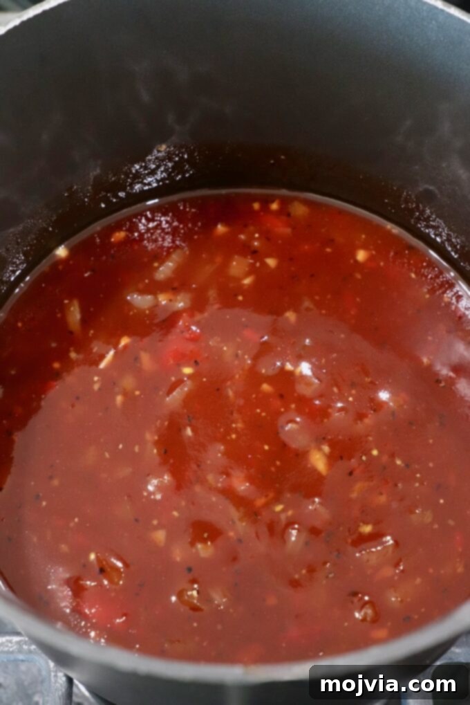 Jack Daniel's: The Taste of Tennessee BBQ 5 A rich, bubbling Jack Daniel's BBQ sauce simmering in a pan on the stove, thickening to a perfect consistency.