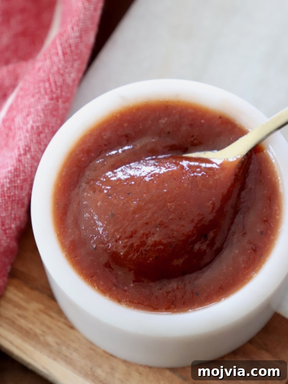 Jack Daniel's: The Taste of Tennessee BBQ 7 A small bowl filled with homemade Jack Daniel's BBQ sauce, garnished with a spoon, highlighting its smooth, glossy texture.