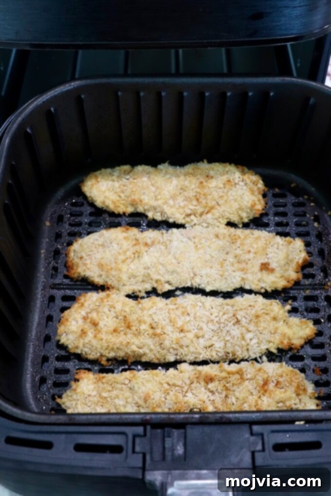 Golden Crispy Air Fryer Chicken 11 cooked breaded chicken tenders in an air fryer basket