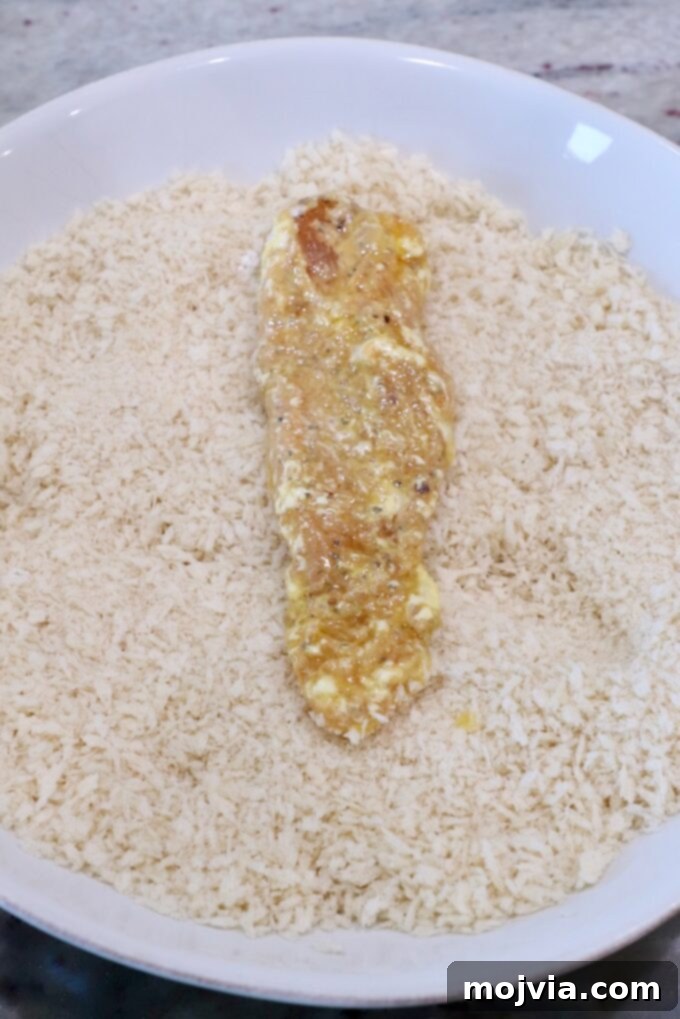 Golden Crispy Air Fryer Chicken 8 strip of battered chicken in bowl of breadcrumbs