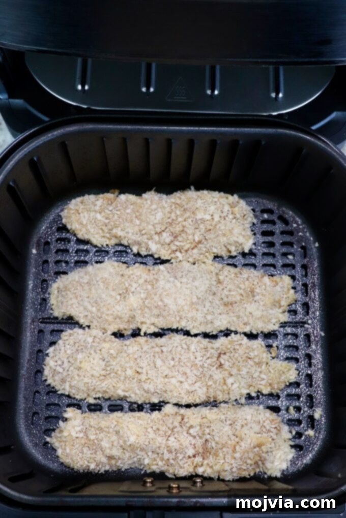 Golden Crispy Air Fryer Chicken 10 uncooked breaded chicken tenders in an air fryer basket
