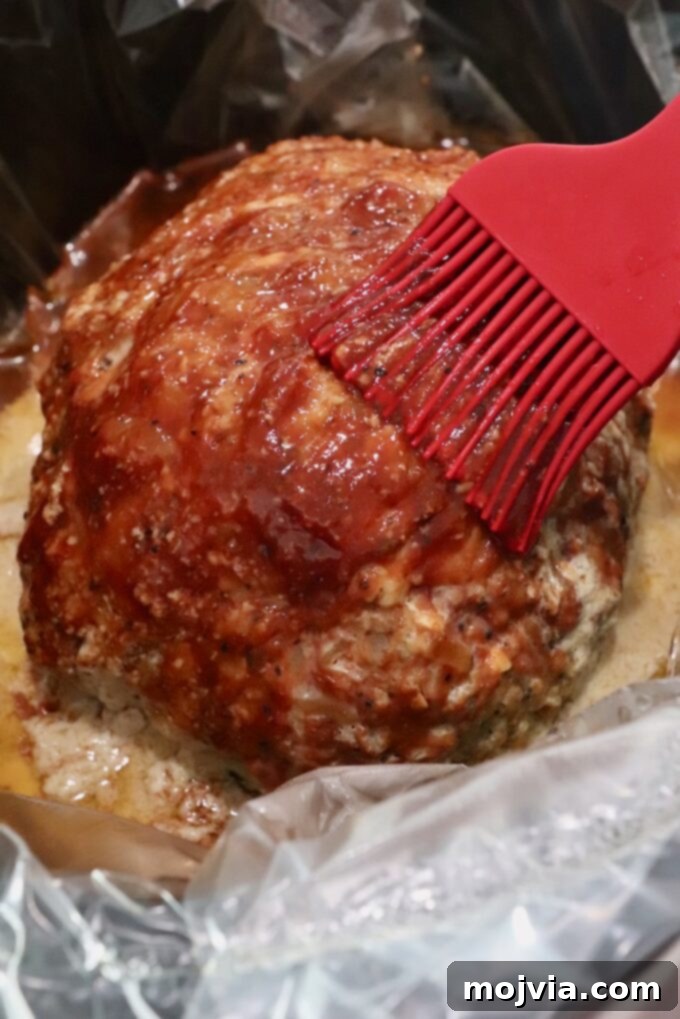 cooked meatloaf in slow cooker brushed with bbq sauce
