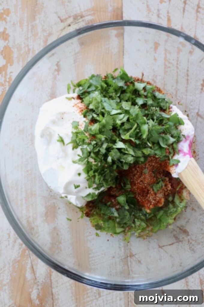 Individual ingredients for southwest salad dressing: sour cream, fresh lime, and a small bowl of dry southwest seasoning with fresh cilantro sprigs.