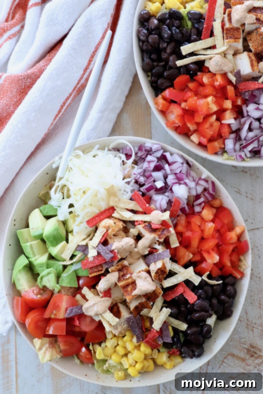A vibrant Southwest Salad in a bowl, topped with diced grilled chicken, avocado, corn, and black beans, drizzled with the creamy dressing.