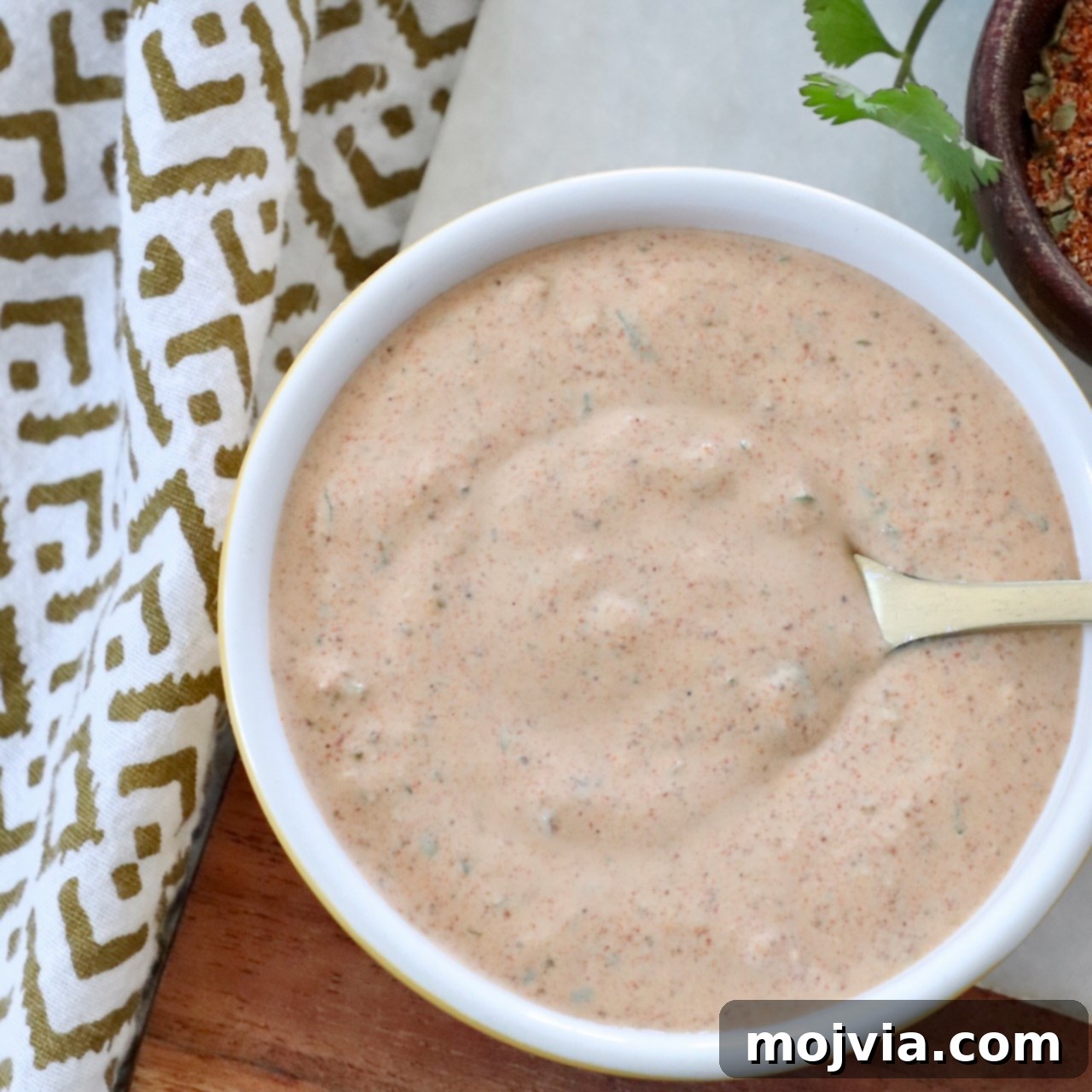 Southwest Salad Dressing in a white bowl with a spoon, highlighting its creamy texture and fresh cilantro.