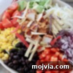 salad in bowl topped with black beans, corn and diced grilled chicken