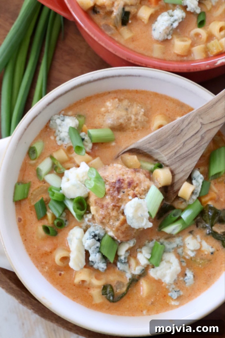 Bold Buffalo Chicken Soup 8 Two bowls of buffalo chicken meatball soup, garnished with green onions and blue cheese crumbles, with a spoon in one bowl.
